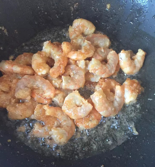 蒜苔炒虾仁,锅里置油，不要等烧热时下腌好的虾仁，油太热会粘锅。炒到虾仁变色盛出备用