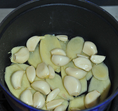 黑椒干锅虾,取一个砂锅或者保温性能好的锅子（我用的是珐琅铸铁锅），把姜和大蒜粒铺满锅底，再倒入三汤匙左右食用油（能铺满整个锅底的量就可以）。