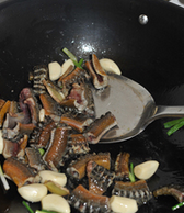 酱烧黄鳝,倒入姜片、葱段和蒜头，一起翻炒几下。