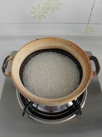 腊味煲仔饭,在砂锅底部抹一层油，再将泡好的大米沥干水放入砂锅，倒入清水（水要超过大米约1cm）。盖上锅盖中小火煮开后再焖煮10分钟左右。