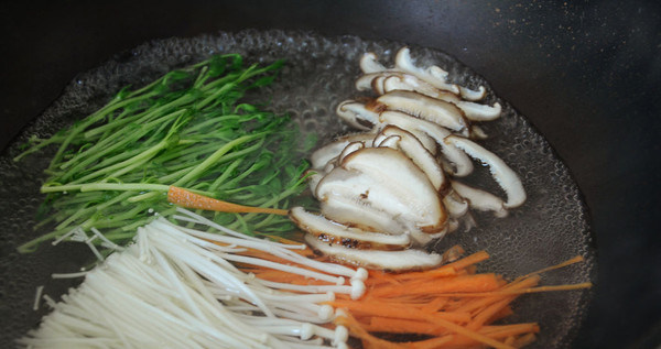 石锅拌饭,锅内烧开水，放入金针菇，，豆苗，香菇，胡萝卜丝烫1分钟，喜欢更熟一点的可以烫久一些