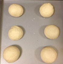 面包超人,发酵结束，将面团取出，排气后分割成6个60克/个的小面团滚圆，其余的面团也滚圆，松弛15分钟。