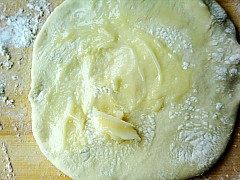 家常葱花油饼,取一份面团擀开，上面抹上适量的猪油。