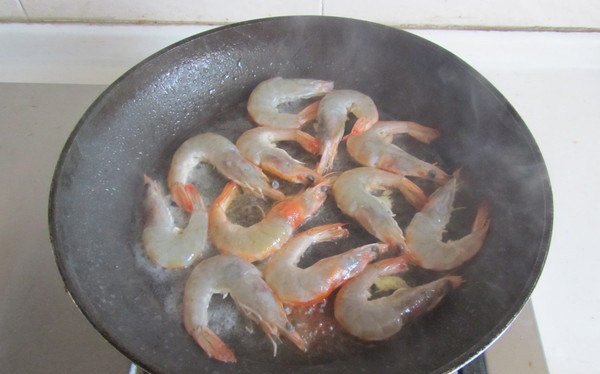 鲜虾炒年糕,锅中放入适量的油， 放入腌制好的虾进去煎