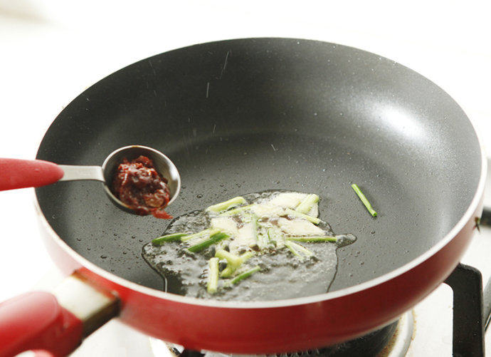 辣爆花蛤,锅内入油，放入葱姜爆香后调入豆瓣酱略炒。