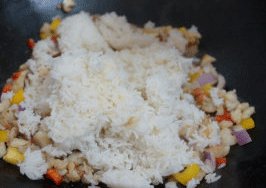 芝士焗龙虾饭 ,加入米饭，将米饭炒散，与材料都炒融合一起，翻炒至米饭上色，然后盛出来稍凉下；