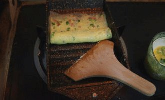 玉子烧,蛋液稍稍凝固后，用煎锅配的木铲快速顺着波浪锅底一格格向前推卷，直至卷到另一头把蛋皮从锅子轻轻卷起。