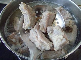 无锡排骨,将腌制好的排骨取出，放入锅内加水浸没，用旺火烧沸，捞出洗净。