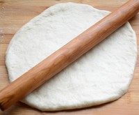 金枪鱼果蔬披萨,在撒上面粉的案板上，将面团擀成烤盘大小的圆饼。