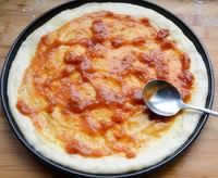 金枪鱼果蔬披萨,在面饼底部涂上适量披萨酱。