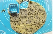 黑芝咸香麻饼干 ,撒一层低粉，将面团擀成约0.2cm的面片，用模具刻成一块块的正方形。