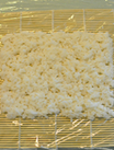 红蟹籽鳗鱼寿司里卷,先将标准尺寸海苔铺满米饭，米饭上盖一层保鲜膜，并翻转过来，使米饭一面向下