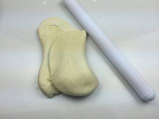 蜜豆小面包,将发酵好的面团取出，用擀面杖擀压排气