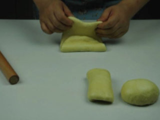 奶香土司,取一个面团，擀成长椭圆形，三分折叠，截面朝下放置