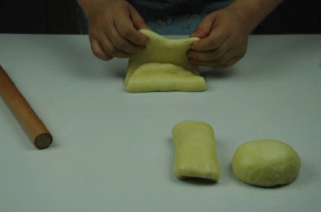 奶香土司,取一个面团，擀成长椭圆形，三分折叠，截面朝下放置