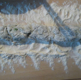 菠菜奶酪圆子,工作台上撒上足量的手粉。取部分菠菜泥，捏成长条圆条。表面也要撒上手粉