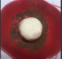 枣泥蘑菇包,全部包好后，用手捏住收口，把枣泥包在可可粉上蘸匀。