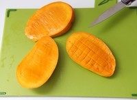芒果水晶果冻,在果肉上用刀划好十字格，别划到底，用手一顶，芒果粒就翻出来了。