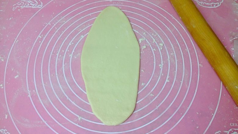 椰香奶酥辫子面包,取一个小面团，擀成椭圆形面皮。