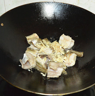 红烧鳝鱼,煎至两面微黄时加入蒜末和姜丝煎香。