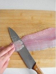 水煮鱼,将鱼皮朝下放置在菜板上，左手轻轻按住鱼肉，右手斜刀片出2毫米厚的鱼片