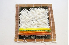 紫菜包饭,将准备好的菜铺在米饭上。