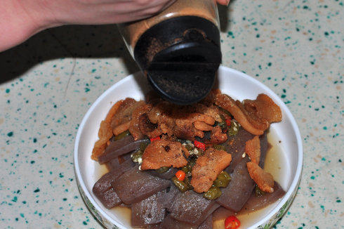 酥香酸辣豆腐,炸好的油渣滤油后加在黑豆腐表面