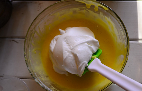 奶牛蛋糕卷,盛1/3蛋白到蛋黄糊中用橡皮刮刀轻轻翻拌均匀(从底部往上翻拌，不要划圈搅拌，以免蛋白消泡)，