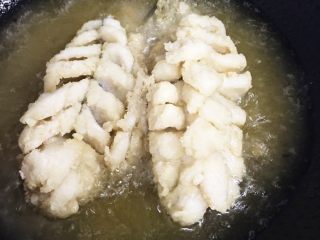 💁松鼠桂鱼🐟,油烧热，手拿鱼尾使切好的鱼花向外用，用勺子向鱼花浇热油，定型后放油锅里炸至金黄捞出，在炸鱼头。