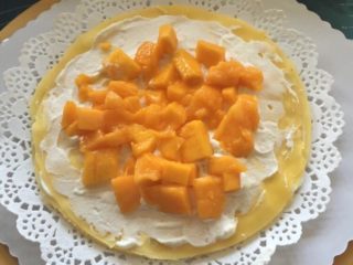 芒果千层蛋糕,再抹一层奶油，加芒果粒，盖一张饼皮。以此类推，一层奶油，一层奶油加芒果粒。直到饼皮用完。