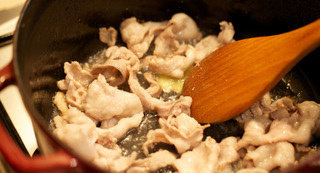 猪肉粥,放入拍扁的蒜和猪五花翻炒至边缘焦糖色