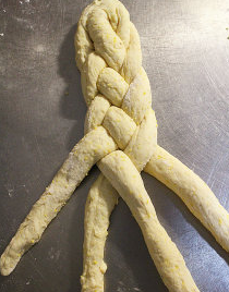早餐玉米软包,每四个长条将组成一个辫子面包.四个面团长条顶部尖端组合捏紧,表面洒些许手粉