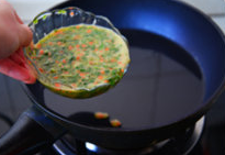 香椿芽胡罗卜蛋饼#春意绿#,锅中放入两大勺油，用手放在锅上试油温，微微热度时就可将蛋液从中间一次性倒入。