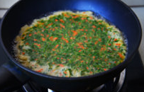 香椿芽胡罗卜蛋饼#春意绿#,迅速转动平底煎锅，让鸡蛋变成蛋饼，中火慢慢煎熟。