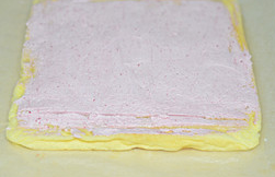 草莓蛋糕卷,烤好的蛋糕出炉凉晾后底部垫一张油纸，翻面后将草莓奶油涂上，头端划二刀不划透。