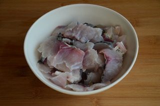 酸菜鱼,将剔完鱼骨的鱼段鱼皮朝下，从尾部开始，斜刀片成鱼片