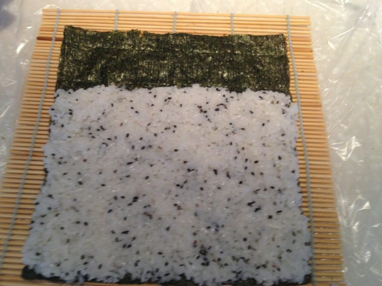 紫菜包饭,将米饭均匀的铺在紫菜上，铺到大约五分之四的位置。铺好后压紧米饭。