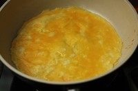 蘑菇蛋卷,平底锅热油，加入一半蛋液平摊成蛋饼。半熟就关小火。