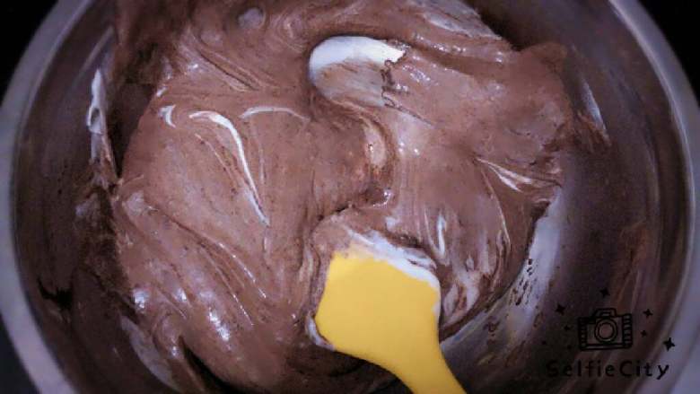 ≈巧克力戚风蛋糕≈,把三分之一蛋白加入蛋黄糊里翻拌均匀