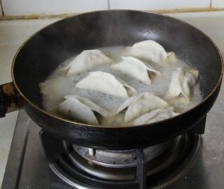 猪肉豆角锅贴,沿锅边淋入冷水，浸没锅贴三分之二左右，盖锅盖焖3分钟左右水干揭盖即可