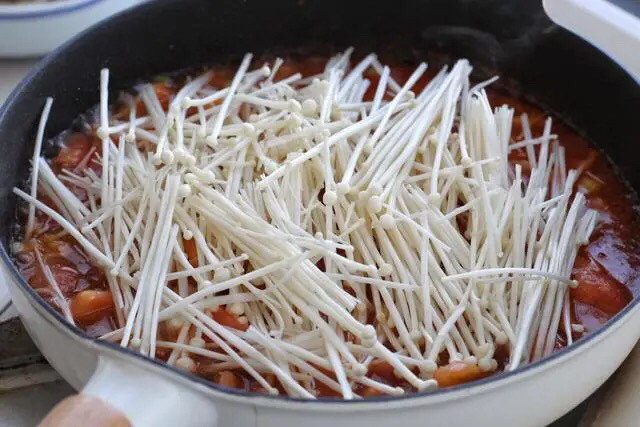 金针菇番茄汤,再倒入二百毫升的清水，把金针菇铺到上面大火煮沸，再改小火煮至金针菇变软、汤汁呈黏稠状态。