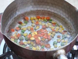 玉米虾仁蛋炒饭,锅中烧开水放入玉米粒杂蔬，焯烫两分钟捞出控水。