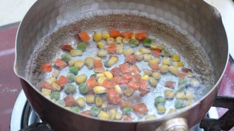 玉米虾仁蛋炒饭,锅中烧开水放入玉米粒杂蔬，焯烫两分钟捞出控水。
