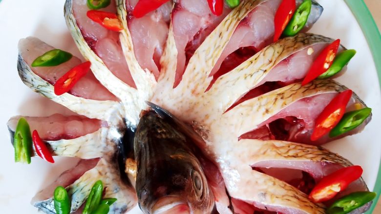 油泼鱼,腌好的鳊鱼切断头尾，中间部分每隔一厘米左右切一刀，注意不要切断。切好的鳊鱼摆盘，