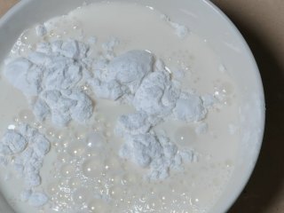 椰蓉小方,将一半的牛奶倒入玉米淀粉内，将其搅拌均匀。