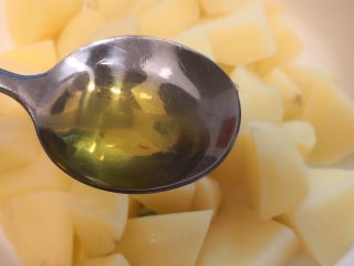 迷迭香土豆,放入一个大一些的容器，加入一勺橄榄油，搅拌均匀