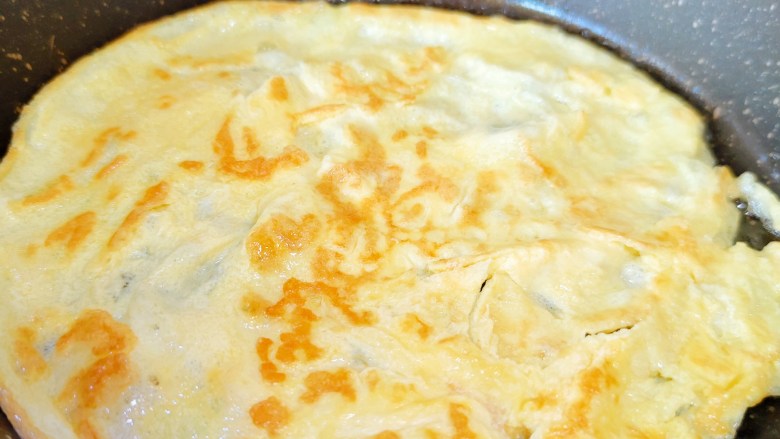 腊八豆拌面,鸡蛋液均匀撒在锅里煎至两面微黄