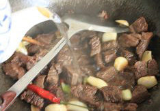红烧牛肉面,炒至酒香夹着肉香的时候，大约一分钟，倒入热开水，末过牛肉的表面，大火烧开