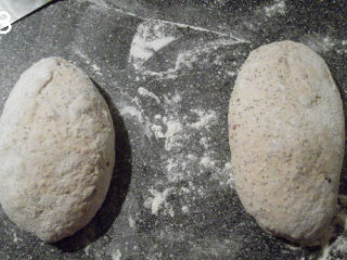 五谷丰登杂粮面包 ,面团倒在撒了手粉的工作台上，分成两份，分别折两次三折。静置10分钟后，塑成像要的形状。塑好的面包放在亚麻布上发酵，表面轻轻撒上层面粉，盖上亚麻布。20度室温下发酵约120分钟