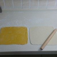 南瓜双色花卷,案板上撒些面粉，双色面团分别擀成
厚3毫米，长25厘米，宽22厘米左的
长方形面片，先在白色面片上刷一层
油